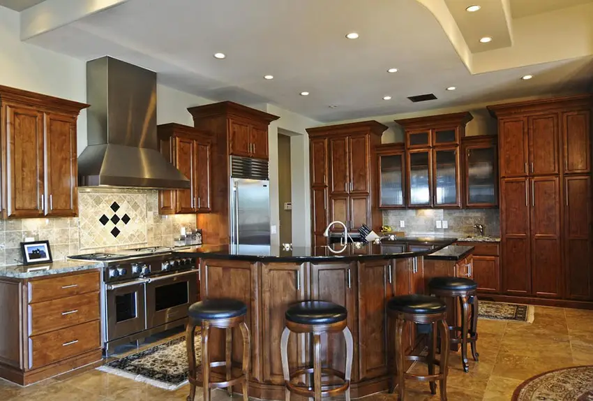 Cabinets in golden walnut finish, light cream tile backsplash and L-shape kitchen island