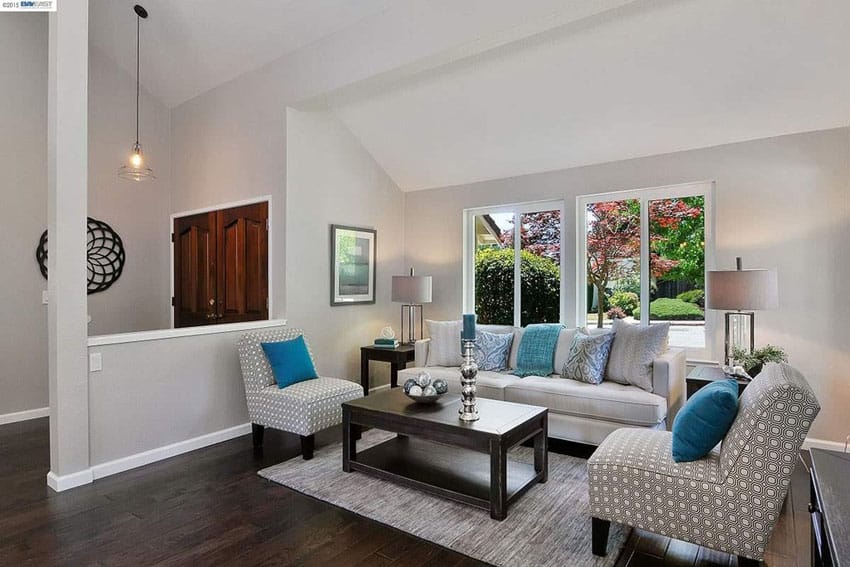 Room with blue pillows, upholstered chairs and half wall divider