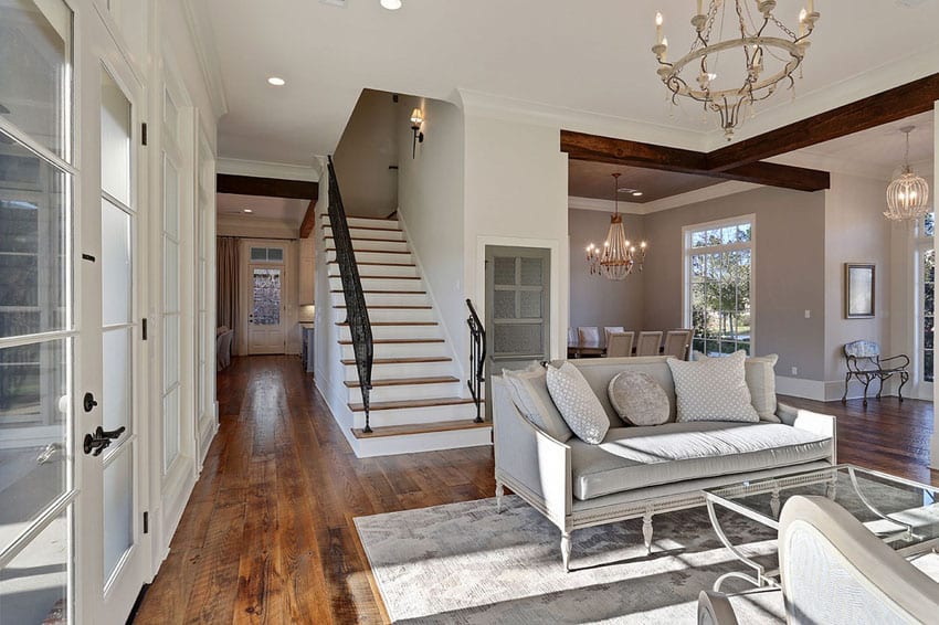 Stairs with white steps and black railings, grey couch and chandelier