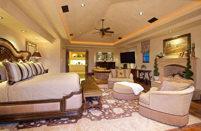 Luxury bedroom with fireplace and raised ceiling with recessed lighting
