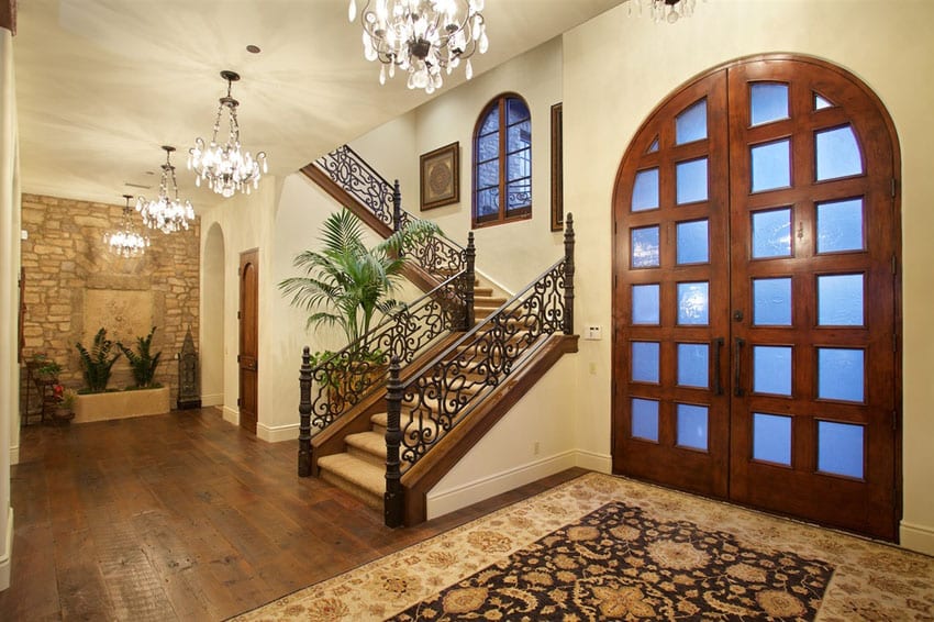 Luxury home foyer with glass chandeliers and large arched doorway