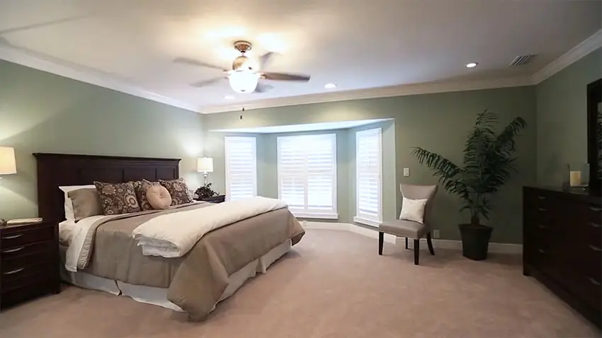 Master bedroom with bay windows, matching furniture and fan