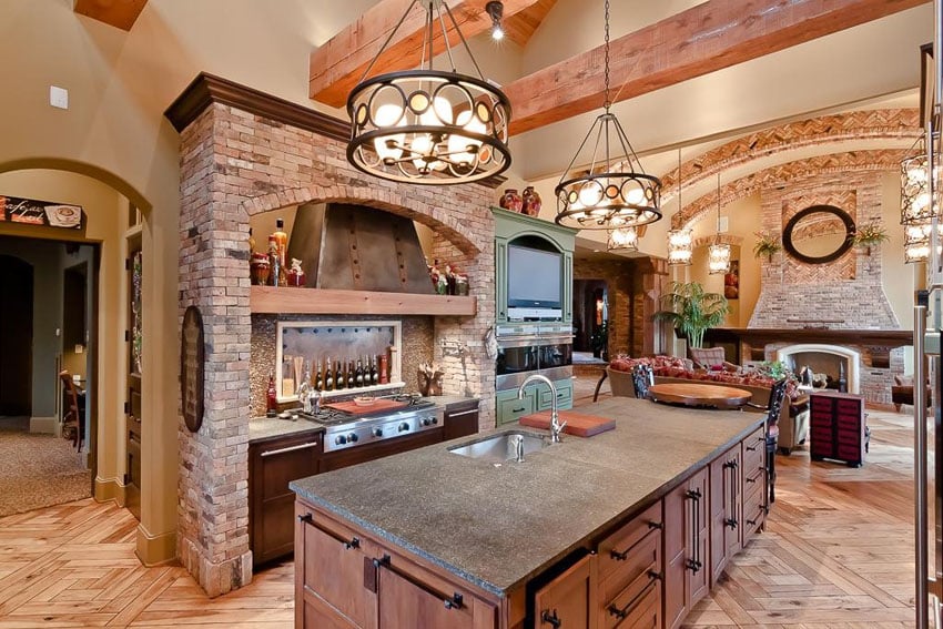 Open layout kitchen with teak abse cabinets and custom handles with brick walls 