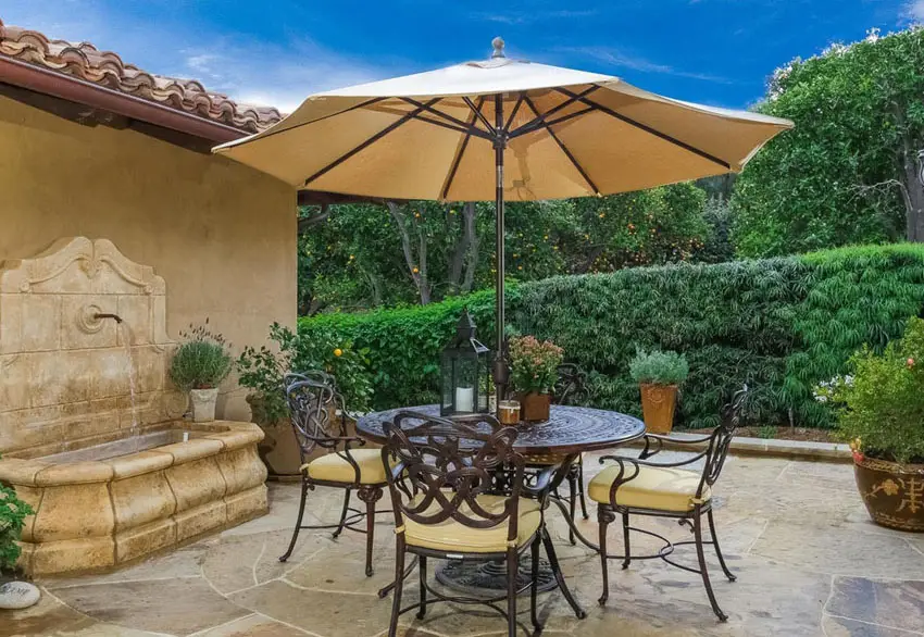 Outdoor patio with water fountain and small round table with umbrella