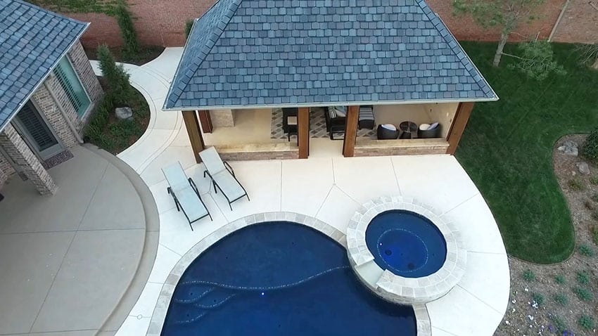 Swimming pool with shingled cabana building with lounge area