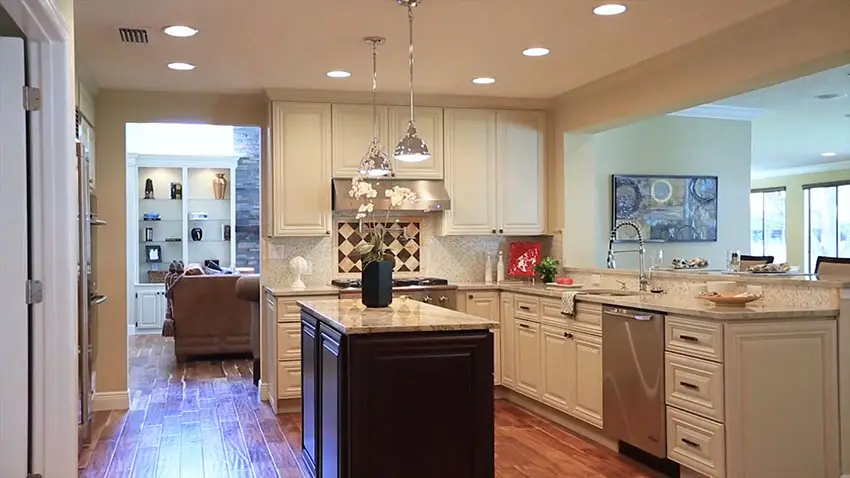 White cabinet kitchen with dark color island and french pendant lights