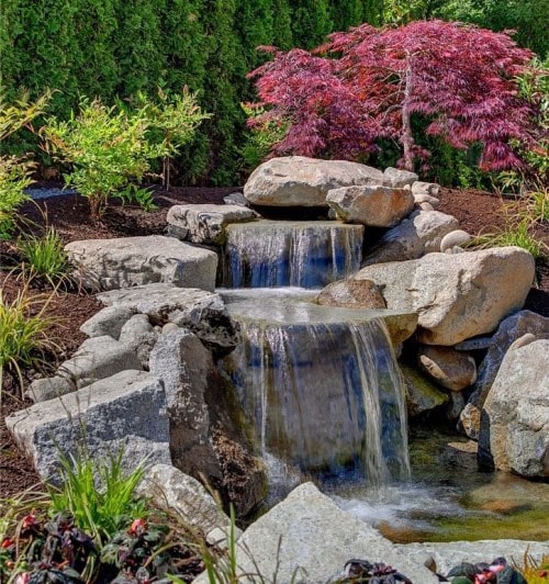Beautiful rock waterfall with colorful plants in the garden