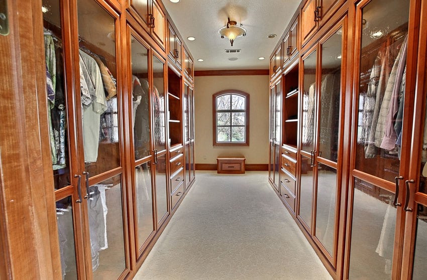 Beautiful wood walk in closet with glass cabinets