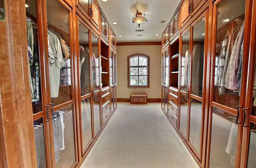 Closet with mahogany cabinet door frames, carpet floors and flush lighting