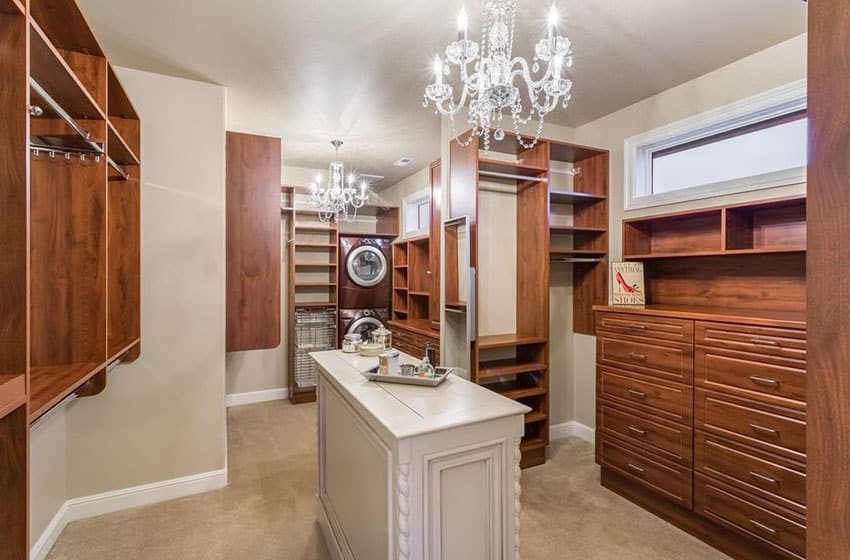 Beige walk-in closet with custom cabinets, island, two chandeliers and carpet