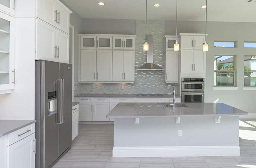 Contemporary kitchen with white cabinets with glass doors and gray quartz countertops