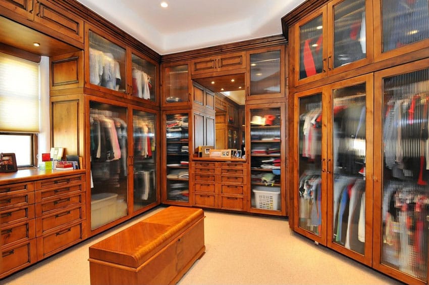 Custom craftsman walk in closet with crown molding frosted glass cabinets