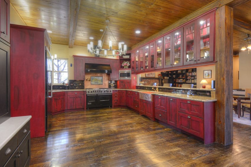 Kitchen with wood panel flooring, weathered look red cabinets and high ceiling