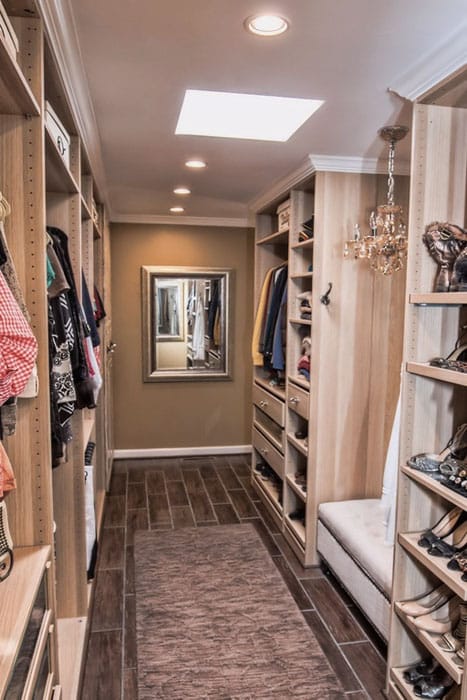 Galley style walk in closet with wood grain floor tiles and small chandelier