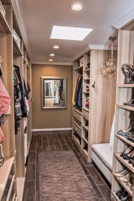 Galley style closet with wood grain floor tiles and small chandelier