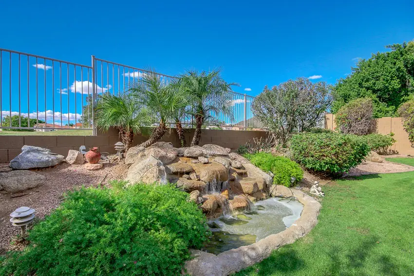 Garden waterfall and small pond in landscaped backyard 