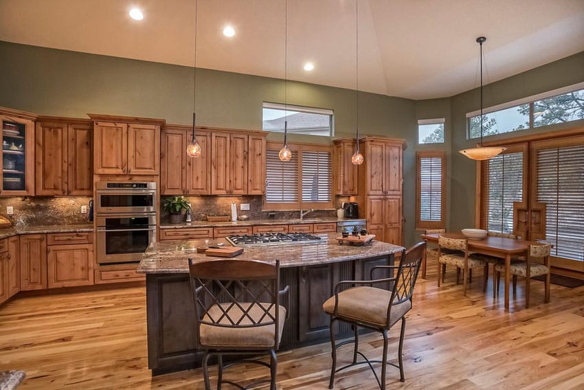 L shaped craftsman kitchen with wood flooring, pendant lights and open to dining table