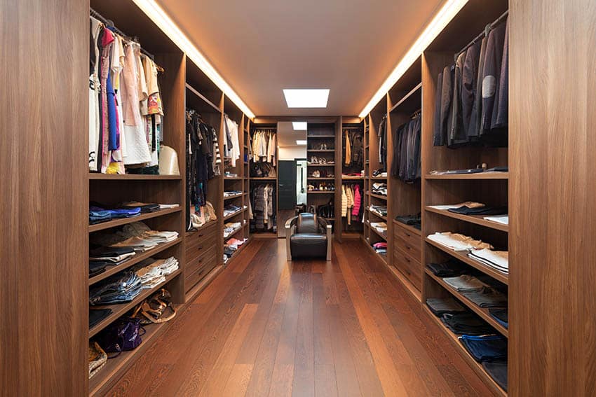 Large luxury wood walk-in closet with masculine design and leather armchair