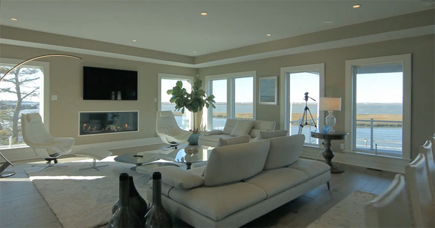 Luxury living room with modern fireplace and wraparound waterfront views