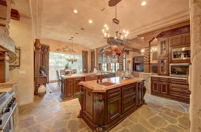 Kitchen with natural stone flooring, natural finish mahogany cabinets and chandeliers