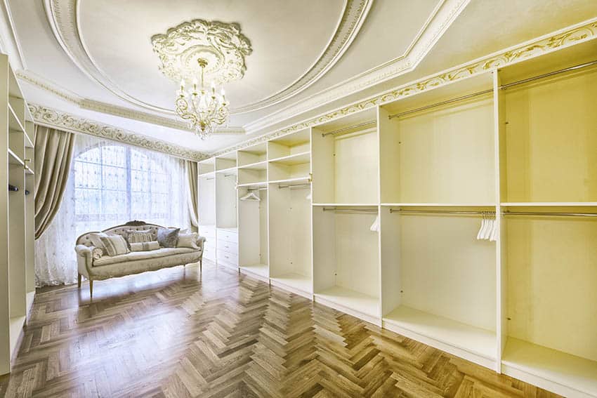 Luxury walk-in closet with chandelier, parquet flooring, arched window and French loveseat