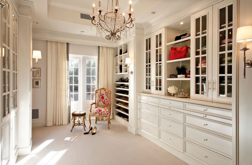 Luxury walk in closet with custom cabinets and window chair with small footstool