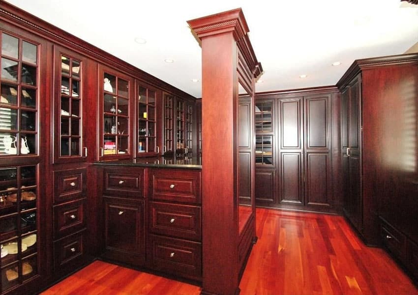 Masculine walk in closet with bright cherry wood floors and raised panel cabinetry