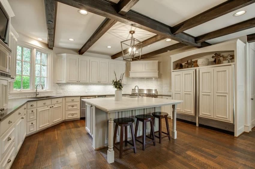 Mediterranean kitchen with white cabinets wood floor and exposed beam ceiling