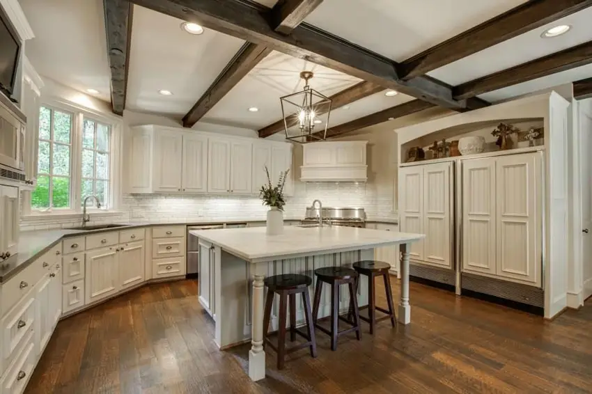 Kitchen with white cabinets, wood floor and exposed beams on the ceiling
