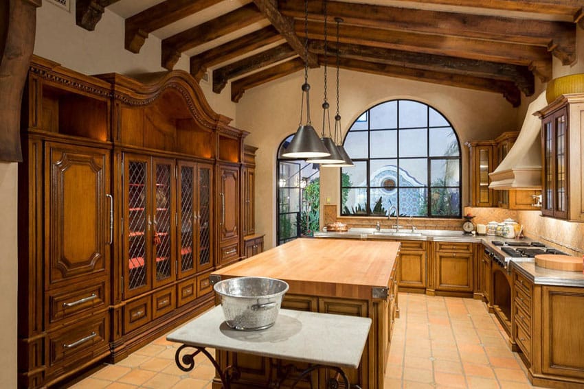 Mediterranean kitchen with wood counter island tile floors beamed ceiling
