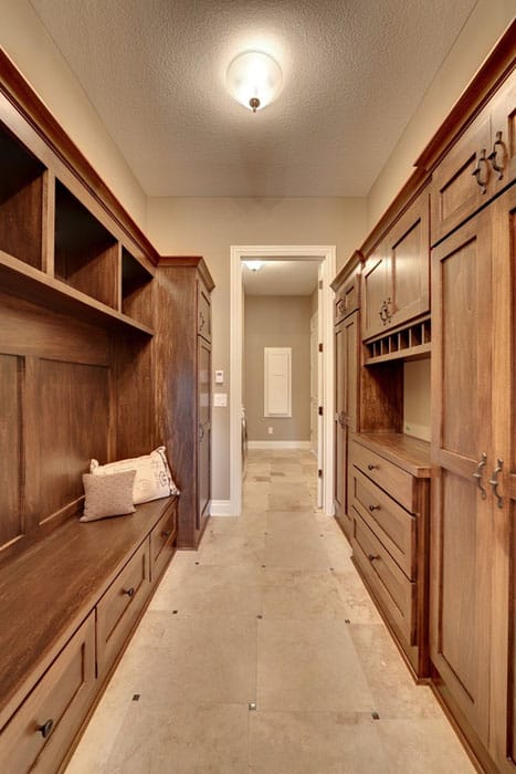 Narrow walk in closet with wood cabinets and marble floor tile