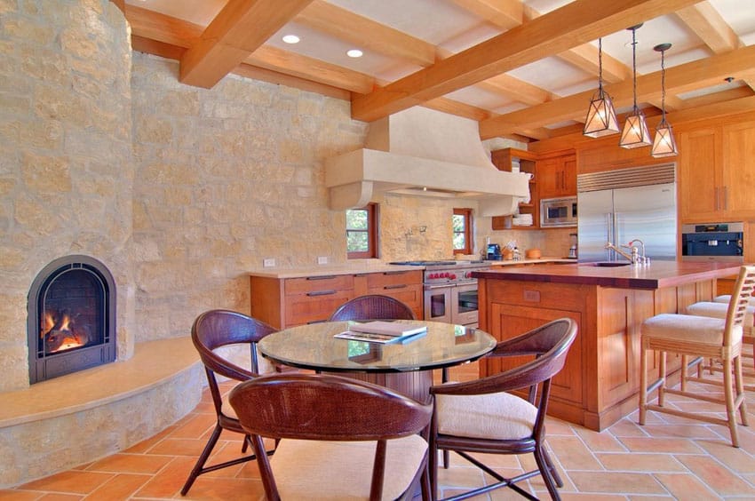 Rustic kitchen with stone wall with fireplace and wood beam ceiling