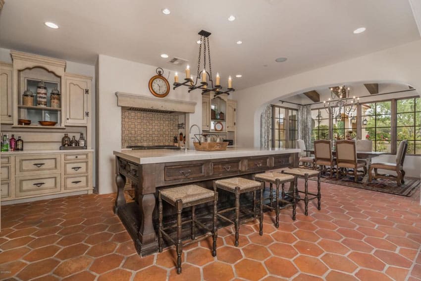 Spanish style kitchen with off white base cabinets dark island terra cotta floors