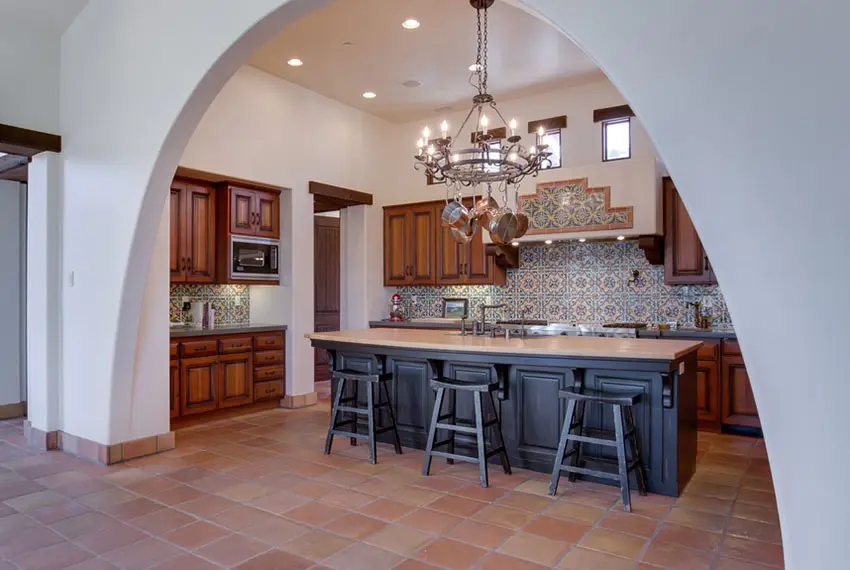 Kitchen with high ceiling, black island and arched doorway