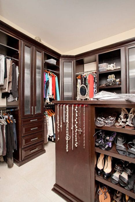 Walk in closet with dark wood cabinetry and travertine floor tiles