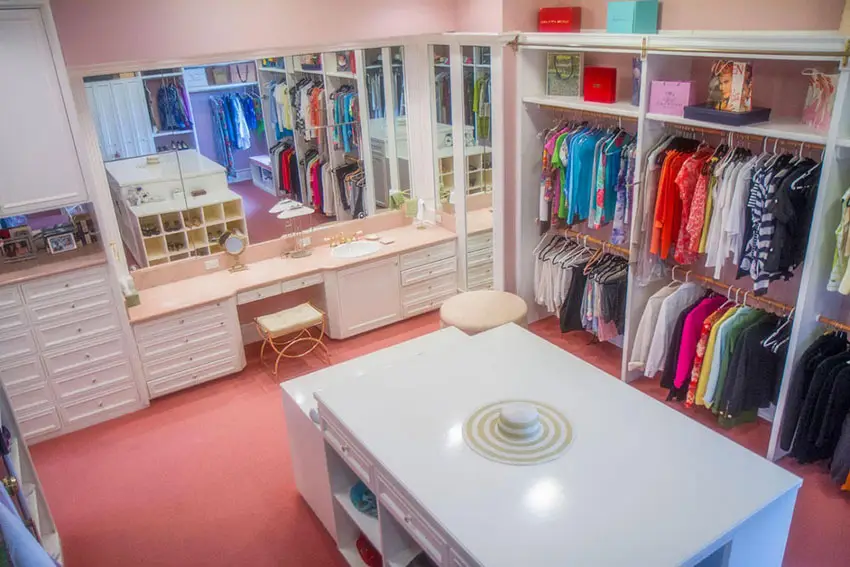 Closet with blush walls and pink flooring and a built in vanity with mirror