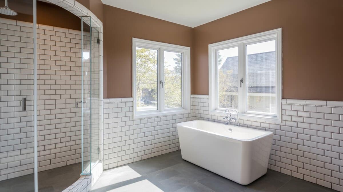 Acrylic freestanding tub by casement windows with mocha and soapstone walls