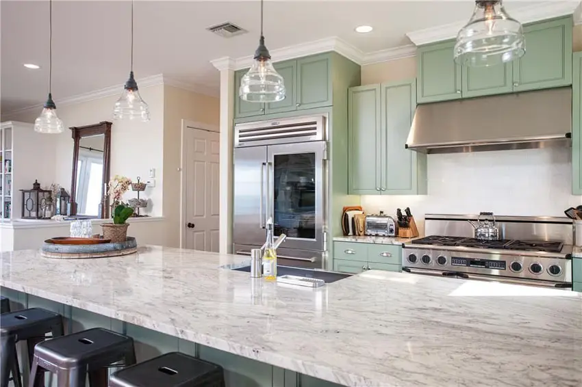 Kitchen with green flat panel cabinets, counter with sink and hanging lights