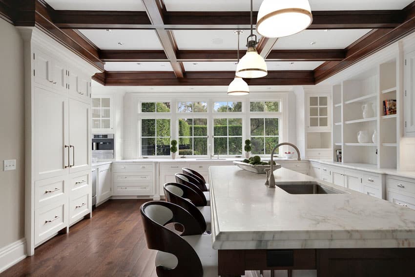 Beautiful kitchen with white cabinets white marble counters and wood coffered ceiling