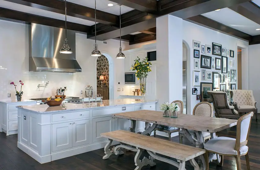 Beautiful luxury kitchen with white shaker cabinetry and rustic picnic style dining table