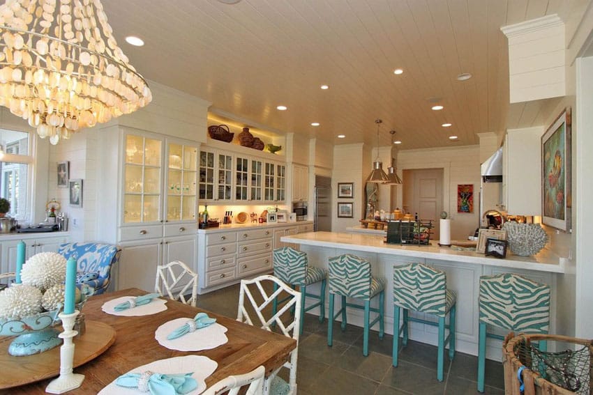 Bright beach style kitchen with marble counters, glass door cabinets and breakfast bar