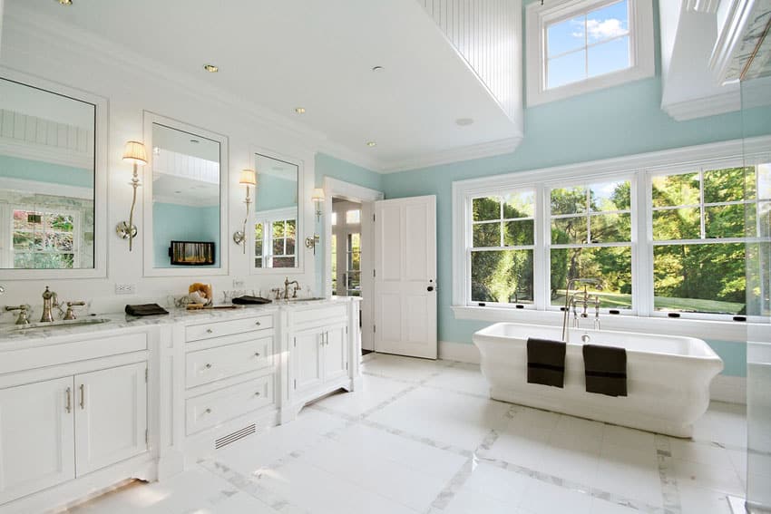 Bright master bathroom with white vanity cabinets and bathtub with picture windows
