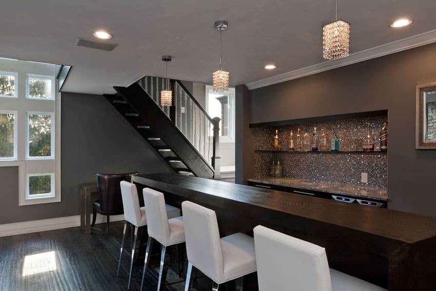 Bar with mosaic tile backsplash in the bar area, white chairs and staircase
