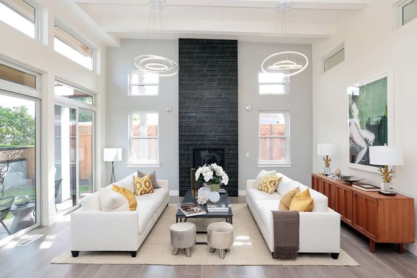 Room with high ceiling, two white couches and modern light fixtures