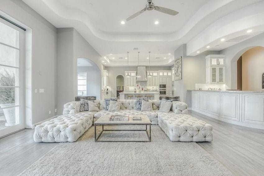 Room with tufted lounge chairs, ceiling fan and island with waincoting 