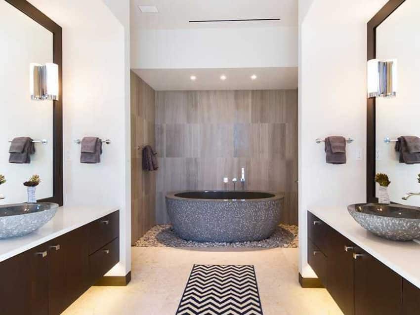 Contemporary master bathroom with custom chiseled stone bathtub surrounded by river rock