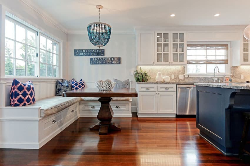 Coastal style cottage kitchen with white cabinets, marine blue island, granite countertops and window seat bench