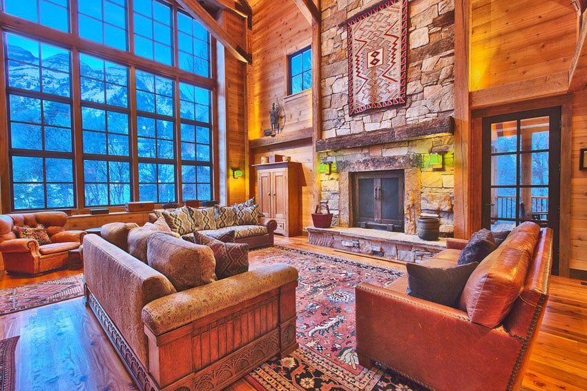 Warm craftsman living room with stone fireplace, hardwood floors, large windows and tall ceiling