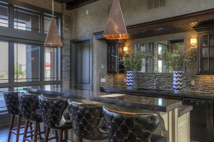 Bar with black stone tiles, tufted stools and white counters
