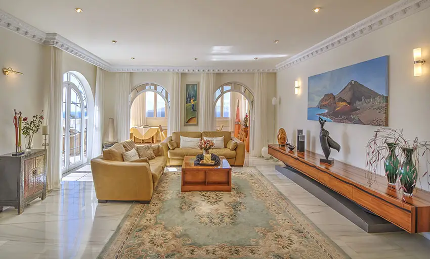 Room with area rug, decorative moldings and arched windows and doorway